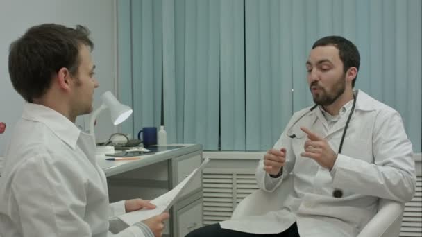 Male doctor and young intern in a good mood talking about new medical researchs - Filmati, video