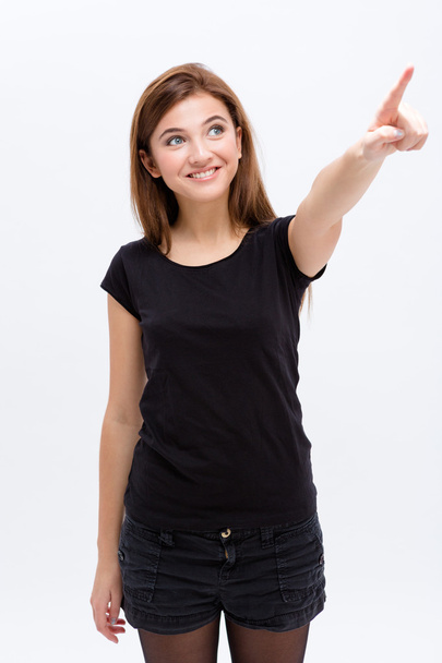 Cheerful lovely cute young woman looking and pointing away - Foto, Imagem