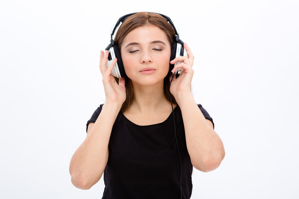 Relaxed serene pretty young woan listening to musi using headphones - Foto, immagini