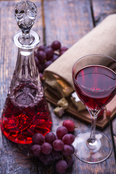Red wine bottle, grapes, walnuts and cheese on a wooden background. Marry Christmas - Photo, Image