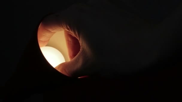 Schroeven van de lamp in een tafellamp in het donker - Video