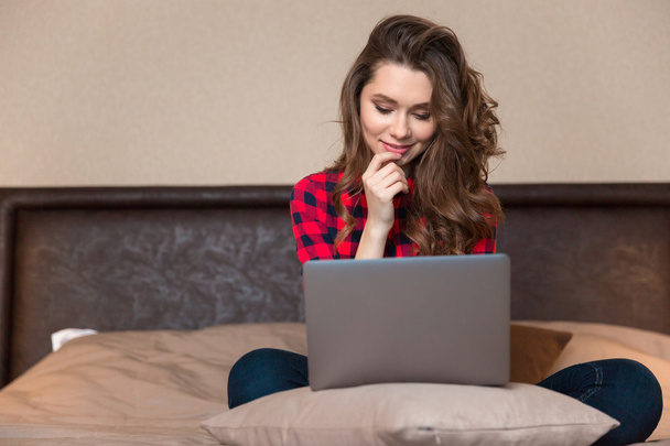 Woman sitting on the bed and using laptop computer - Foto, Imagen