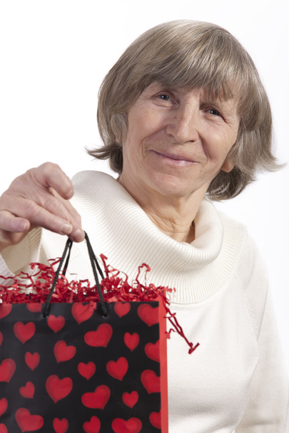 Senior woman raising gift bag - Foto, afbeelding