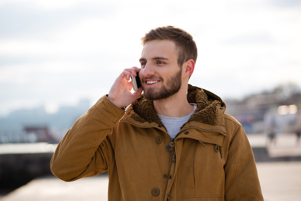 Smiling man talking on the phone outdoors - Foto, imagen