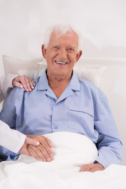 Smiling elderly patient in bed - Foto, afbeelding
