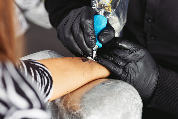 Tattoo artist works on the client's hand - Foto, imagen