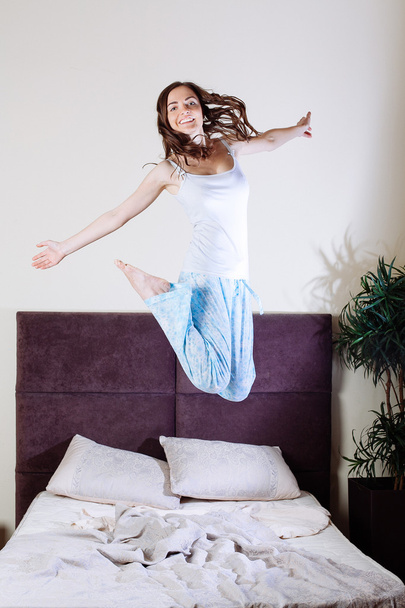 Happy young woman jumping on bed - Foto, Imagen