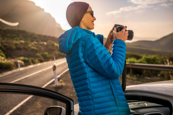 Female traveler photographing sunrise near the car - 写真・画像