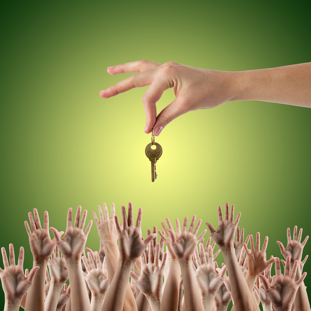 REAL ESTATE concept. Many hands want to get the key, reaching out for key - concept of winning a house, apartment. Close up view of hand holding key to a dream house. Clipping pass and copy space. Green background - Photo, Image