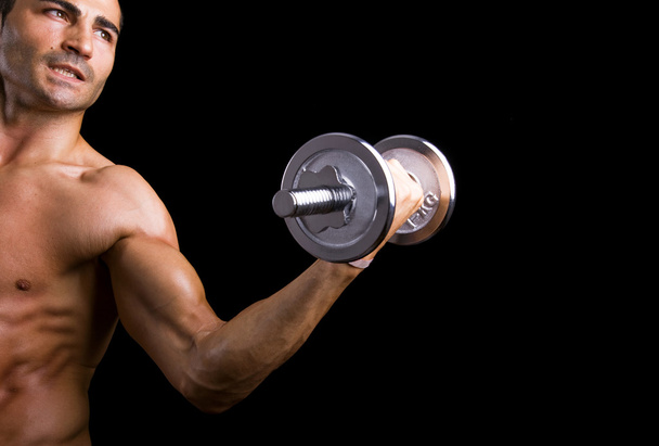 Poderoso homem muscular levantando pesos sobre fundo preto
 - Foto, Imagem