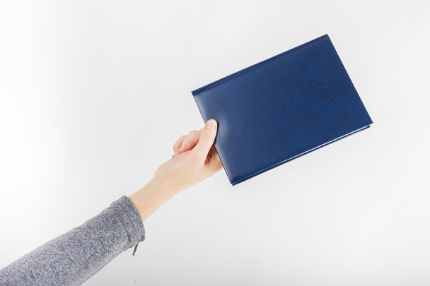 Showing woman holding book diary with copy space for your text or design. High angle view on white background. - 写真・画像