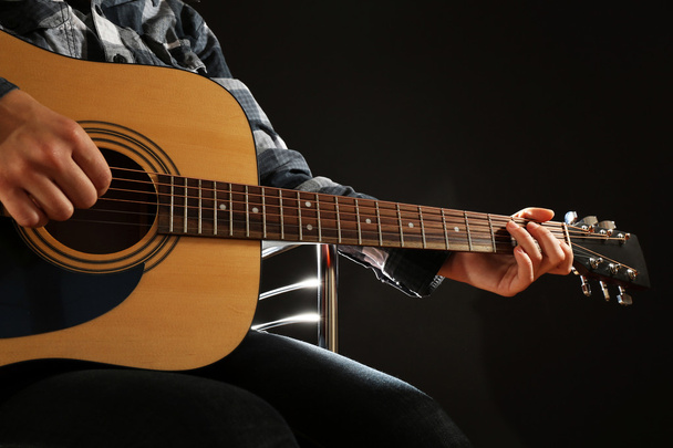 Musician plays guitar on black background, close up - Photo, Image