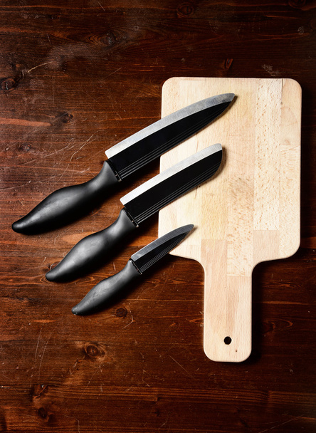 keskin bıçaklar ve koyu ahşap masa üzerinde kesme tahtası - Fotoğraf, Görsel