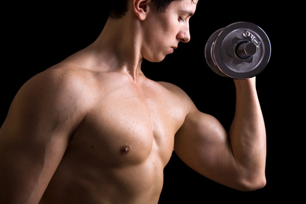 Muscular young man lifting dumbbells on black background. - Fotoğraf, Görsel
