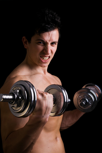 Powerful muscular young man lifting weights - Fotó, kép