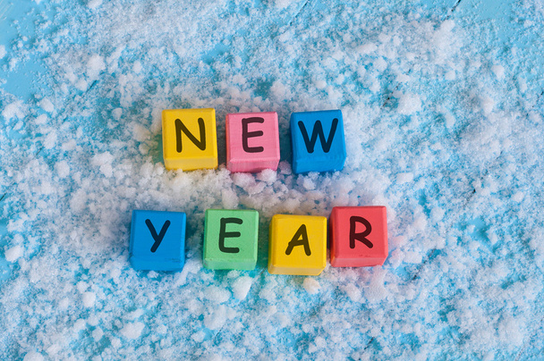 happy new year written with toy color cubes. on snow background - Photo, Image