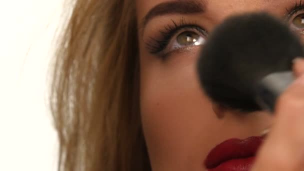 Makeup artist applying shimmer powder on woman face. close up - Záběry, video