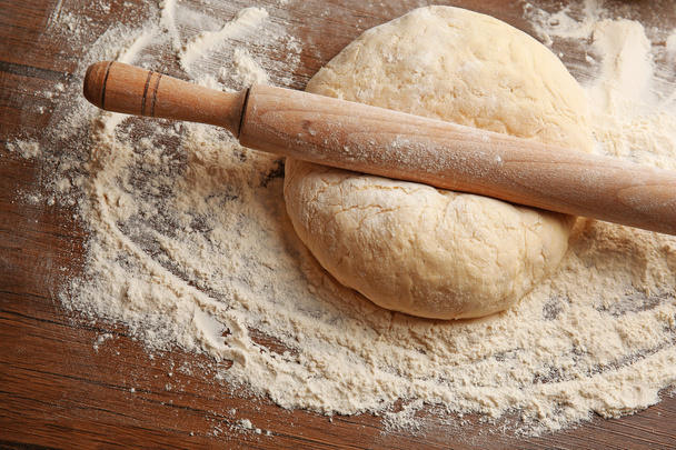 Dough for pizza and rolling-pin on wooden table - Fotoğraf, Görsel