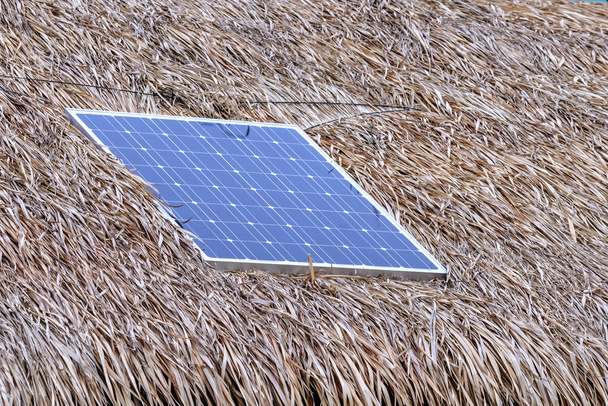 Zonnecel op rieten dak voor energie in bos. - Foto, afbeelding