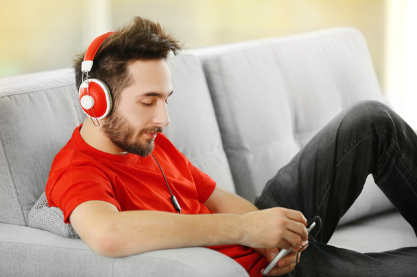 Młody człowiek słucha muzyki w słuchawkach  - Zdjęcie, obraz