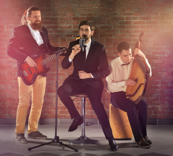 Man's musical band on brick wall background in the studio - Photo, Image