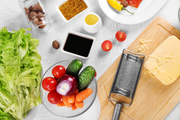 Kitchen utensils and ingredients for salad on table, on light background - Фото, изображение