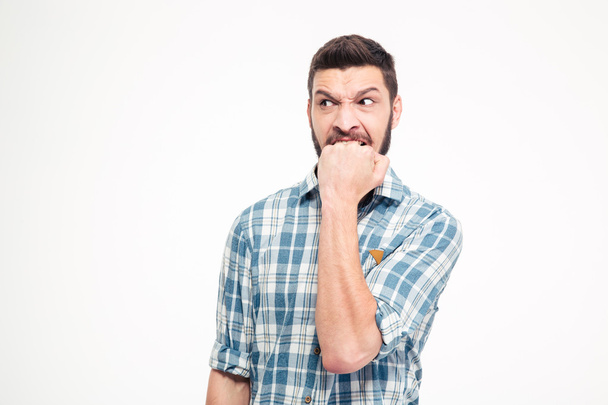 Angry irritated aggressive young bearded man biting his fist - Foto, Imagen