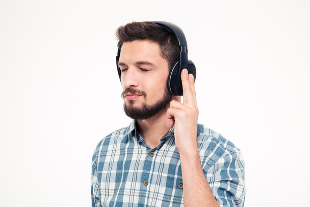 Relaxed thoughtful young man listening to music using headphones  - Fotó, kép