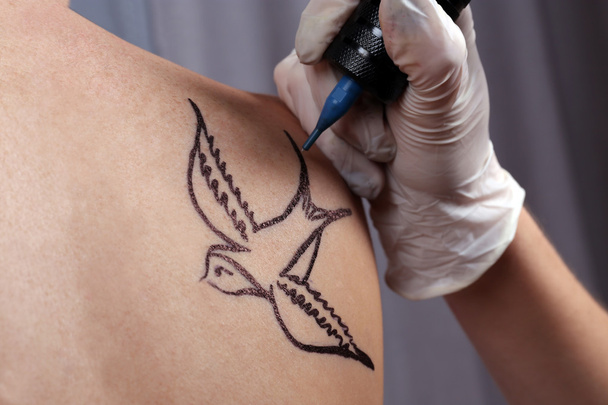 Tattooist drawing swallow - Foto, Imagen