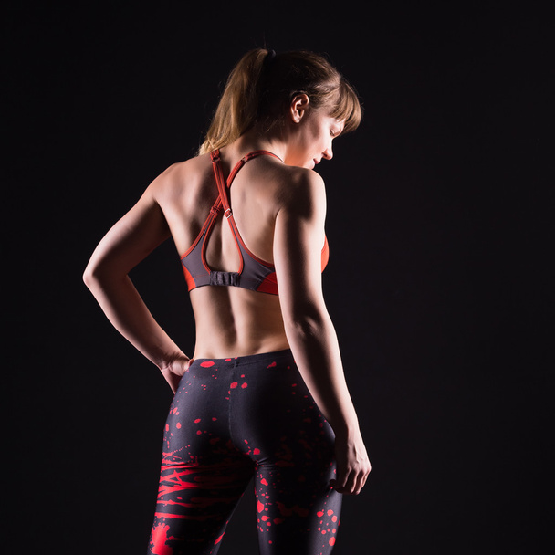 Beautiful young and fit fitness sport model posing in dark studio - Фото, зображення