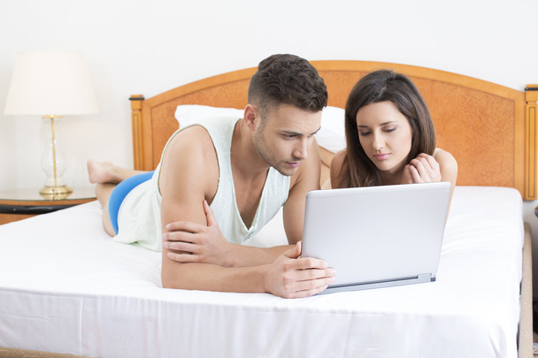 Couple in bed looking at laptop together - Фото, зображення