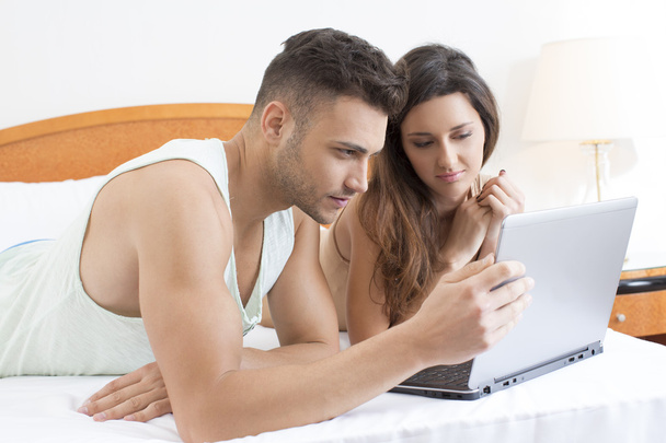 Couple in bed looking at laptop together - Фото, зображення