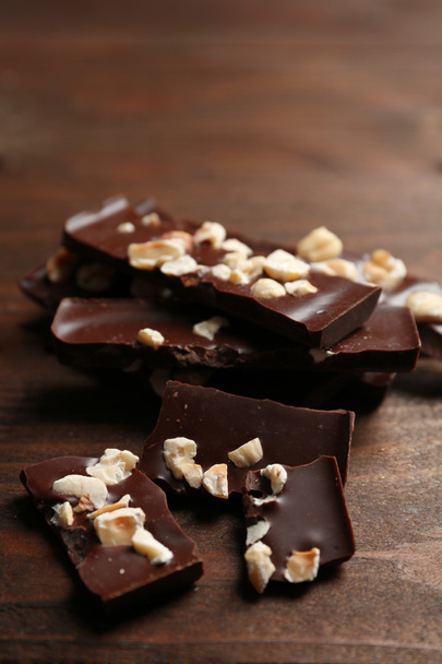 Chocolate pieces with nuts on color wooden background - Φωτογραφία, εικόνα