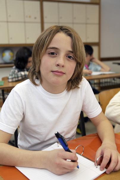 Шкільний хлопчик сидить за столом
 - Фото, зображення