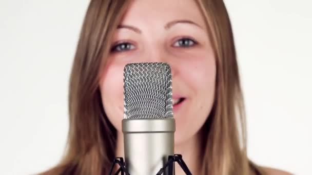 Beautiful girl singing into a studio microphone and looks into the camera. - Footage, Video