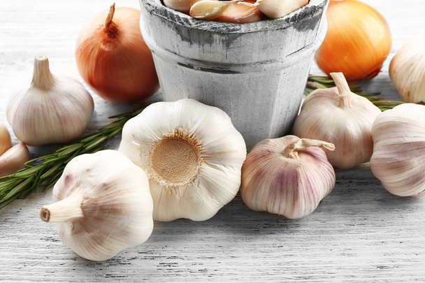 Composition of garlic, onion and rosemary on wooden table, close up - 写真・画像