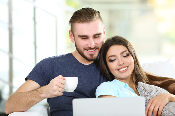 Happy couple sitting on sofa with coffee - Foto, imagen