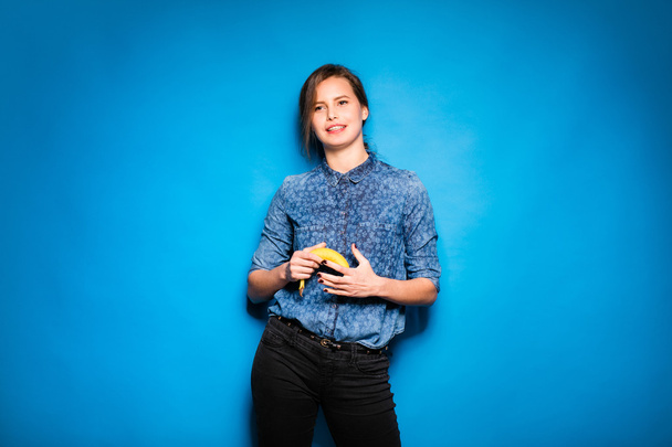 woman with banana in hands on blue background - Foto, Imagem