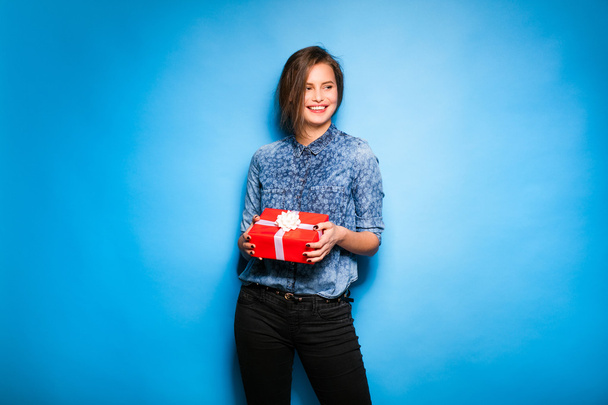 young woman holding red gift in hands - 写真・画像