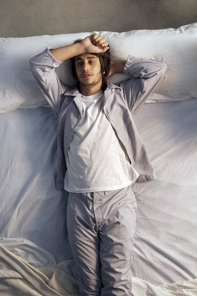 Молодой человек лежит в постели - Фото, изображение