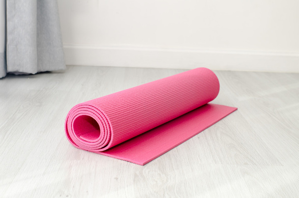 Pink yoga mat on gray floor at home.  Health concept. - Фото, изображение