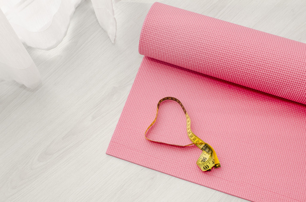 Yoga mat and  measuring tape on floor.  Love health concept. - Photo, image