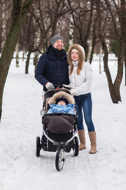 Happy young family walking in the park in winter - Фото, изображение