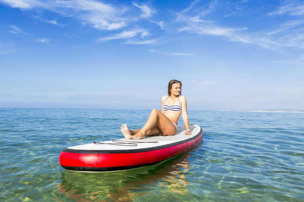 Woman sitting over a paddle surfboard - Photo, Image