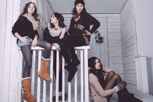 Four stylish models posing sitting on the fence - 写真・画像