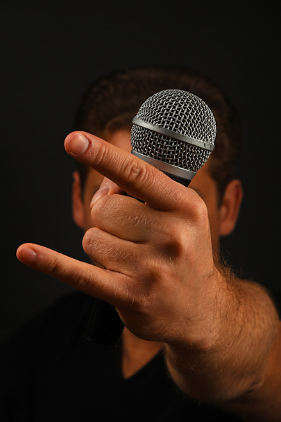 Χέρι με το μικρόφωνο και το διάβολο κέρατα που απομονώνονται σε μαύρο - Φωτογραφία, εικόνα
