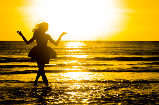 beztroski Kobieta tańczy w zachód słońca na plaży. vita wakacje - Zdjęcie, obraz
