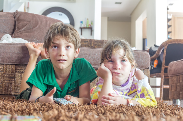 двое маленьких детей смотрят телевизор дома
 - Фото, изображение