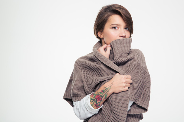 Pensive sad woman with tatoo hiding lipd behind knitted jacket  - Φωτογραφία, εικόνα