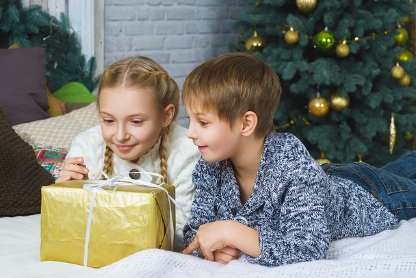 Happy boy and girl lying on bed. Next to gifts. Waiting for Christmas. Celebration. New Year. - Foto, immagini